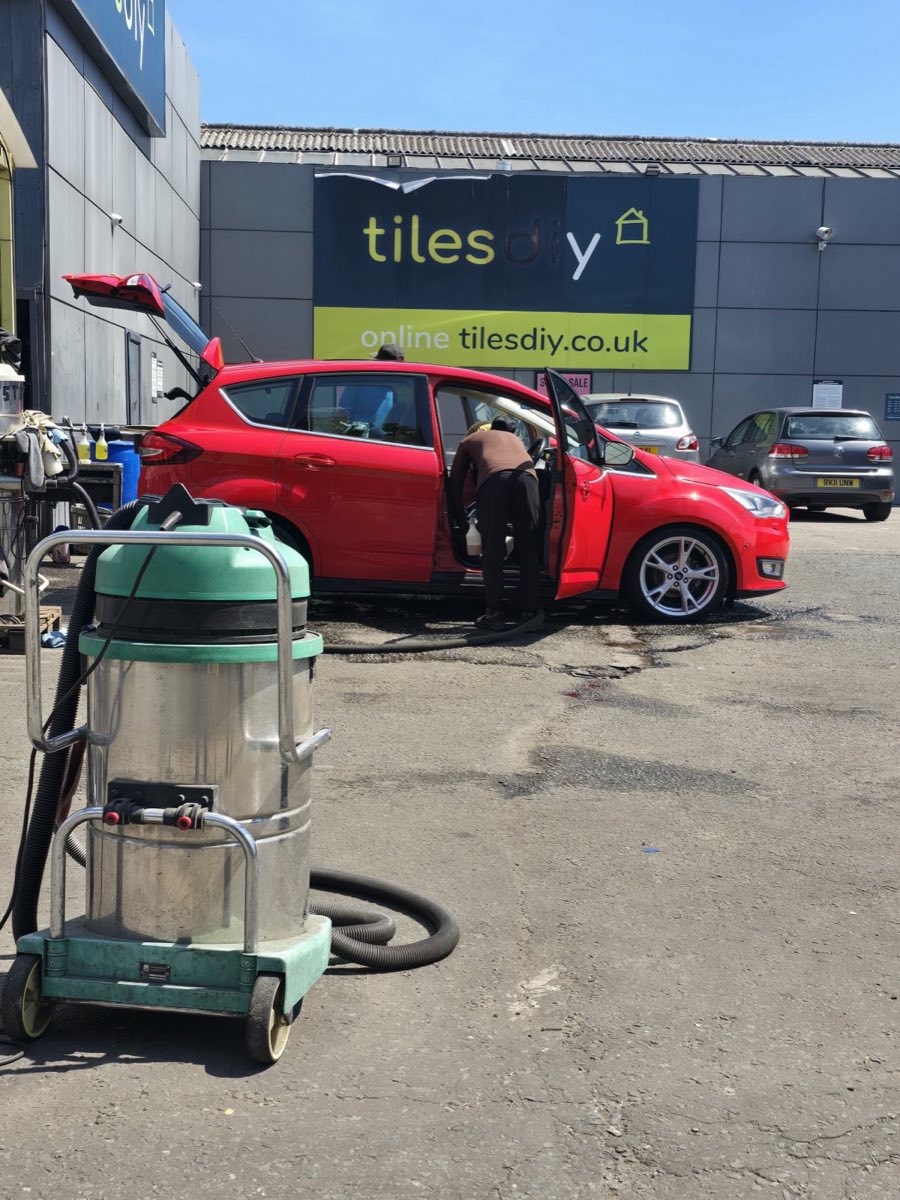 A red Ford being cleaned inside and out with the doors open at Pit Stop, next to the Tiles DIY showroom in Newbury Park.